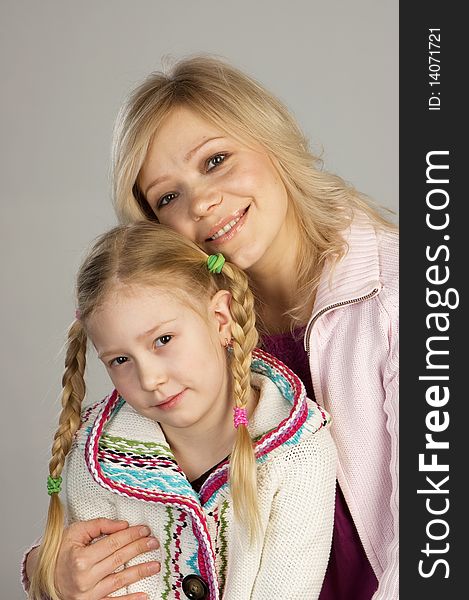 Happy woman with daughter, studio shot, gray background. Happy woman with daughter, studio shot, gray background
