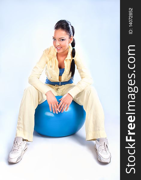 Beautiful girl sitting on the big blue ball, studio shot. Beautiful girl sitting on the big blue ball, studio shot