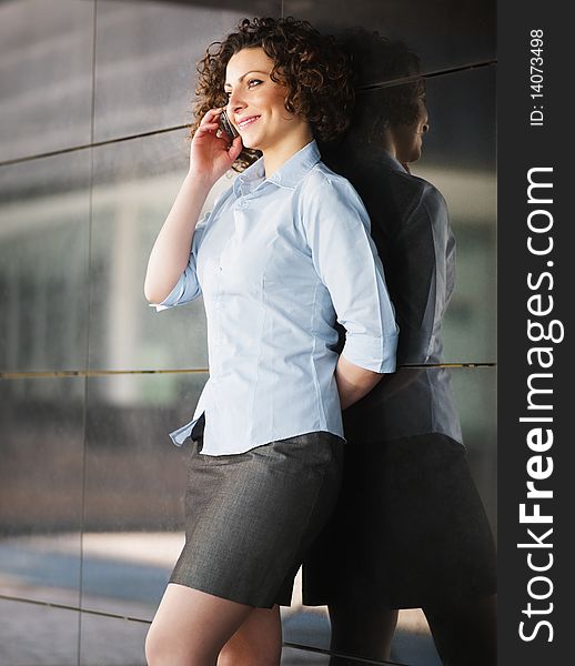 Italian businesswoman talking on mobile phone outdoors and smiling. Vertical shape. Italian businesswoman talking on mobile phone outdoors and smiling. Vertical shape