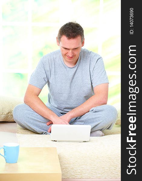 Portrait of a man relaxing on sofa in home with laptop and smiling. Portrait of a man relaxing on sofa in home with laptop and smiling.