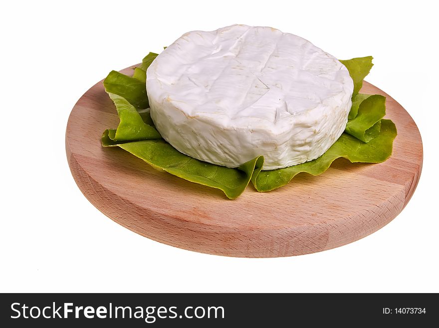 Round camembert cheese on lettuce on cutting board. Round camembert cheese on lettuce on cutting board.