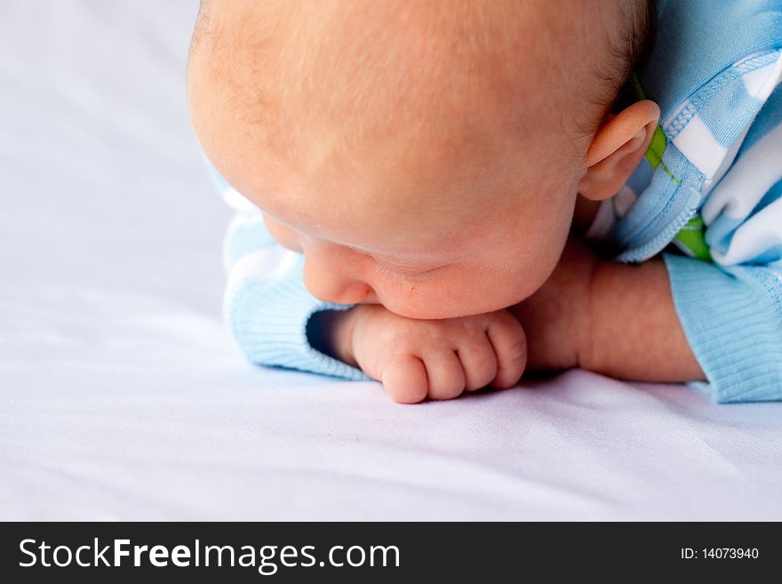 A very young baby boy child is photographed while he is 0-3 months old infant.