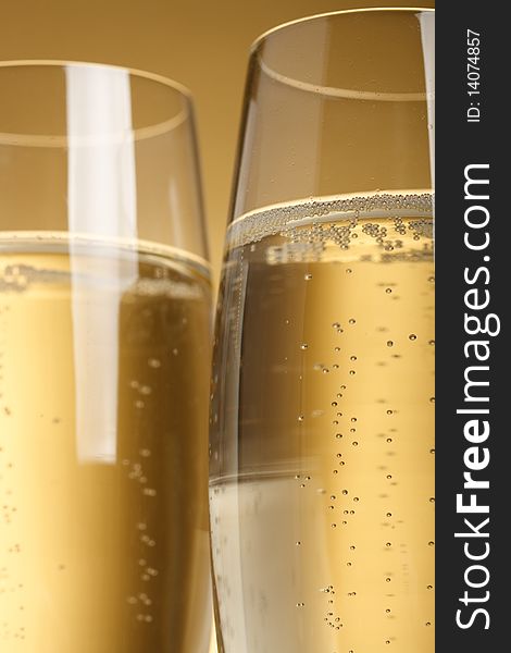 Two flutes with champagne on golden background. Two flutes with champagne on golden background