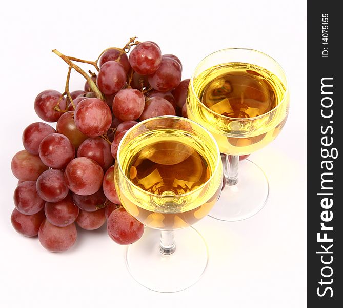 Two glasses of white wine and red grapes on white background