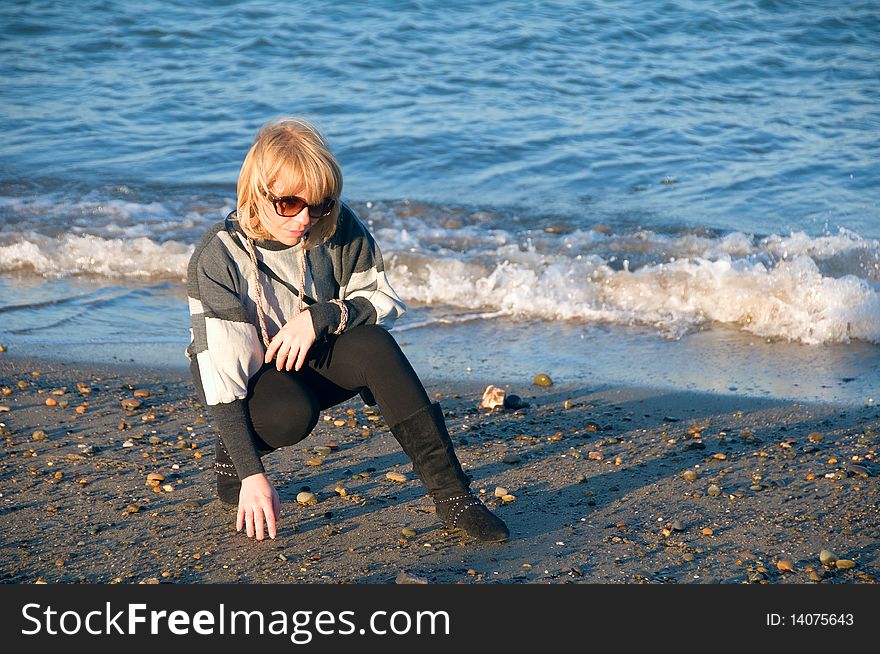 Young woman on the beach picking rocks