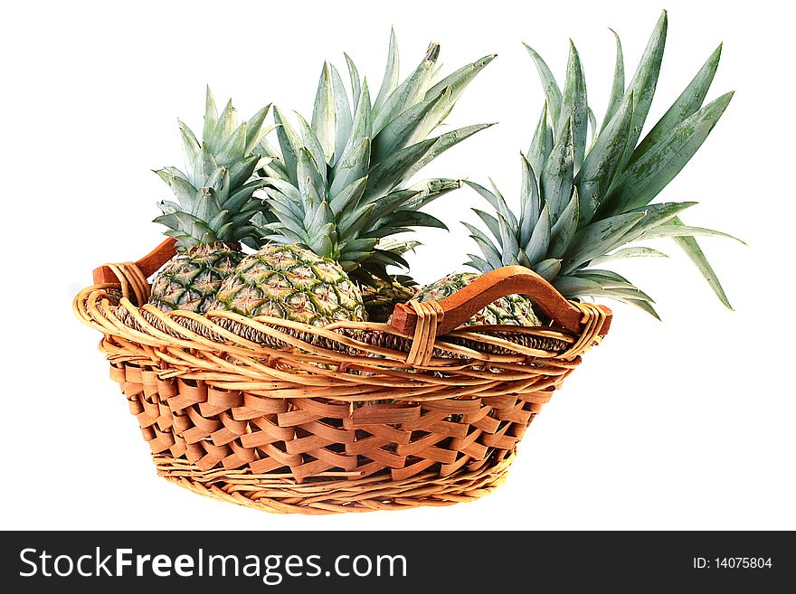 The crop of pineapples is collected in a wattled basket, a background white. The crop of pineapples is collected in a wattled basket, a background white.