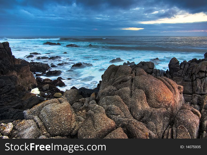 Foreground rocks frame the waves crashing at Monterey at sunrise. Foreground rocks frame the waves crashing at Monterey at sunrise