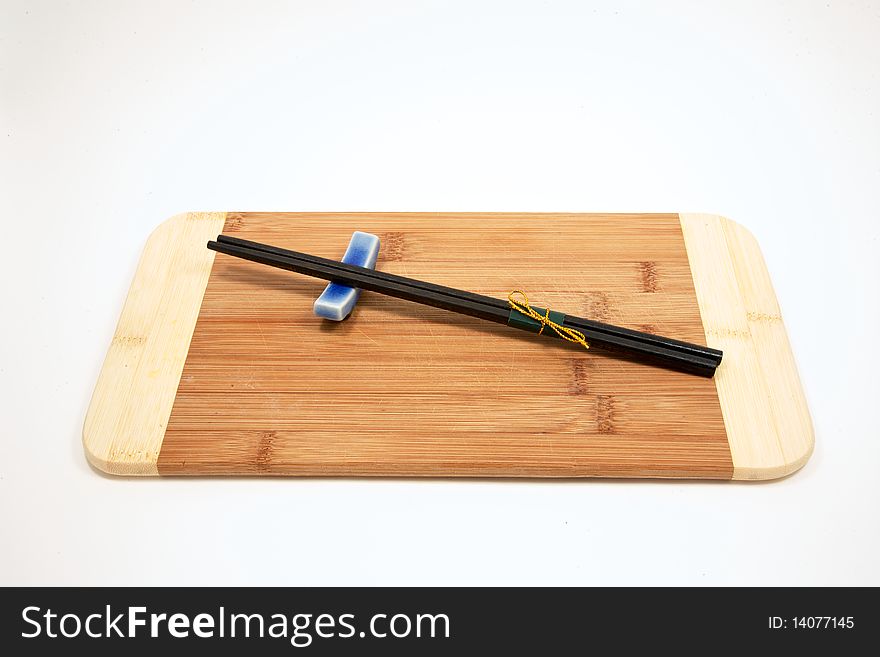 Two chopsticks resting on a blue glass holder on a bamboo board. Two chopsticks resting on a blue glass holder on a bamboo board
