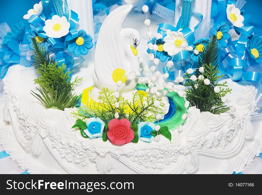 White wedding cake against with white swan on top and flowers