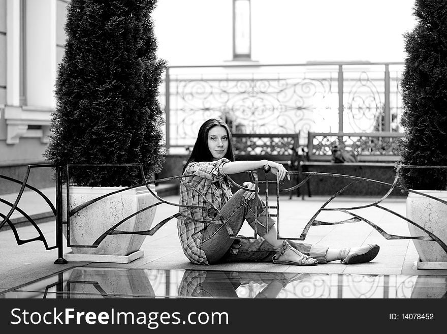 Girl sitting on floor near fence. Girl sitting on floor near fence