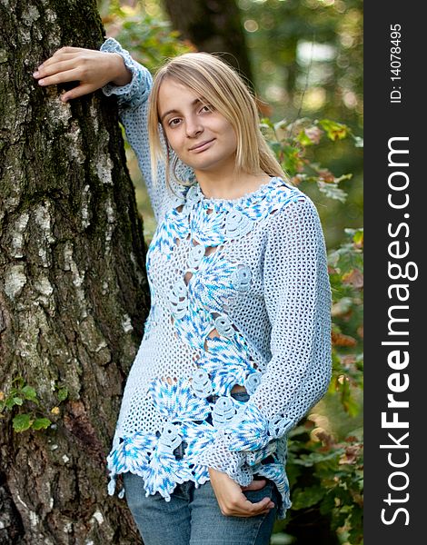 Sunburned girl in blue pullover between two birches