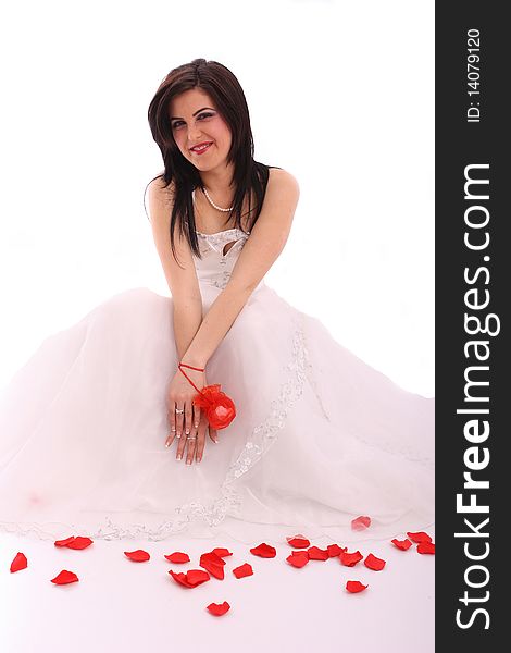 Happy young bride in wedding dress with rose petals on white background
