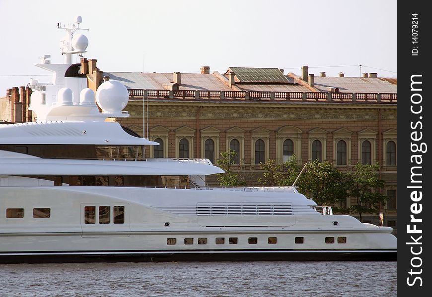 Modern white yacht opposite old building