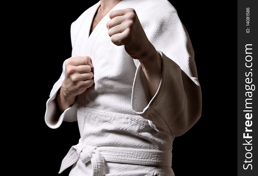 Karateka in white kimono isolated on black background. Karateka in white kimono isolated on black background