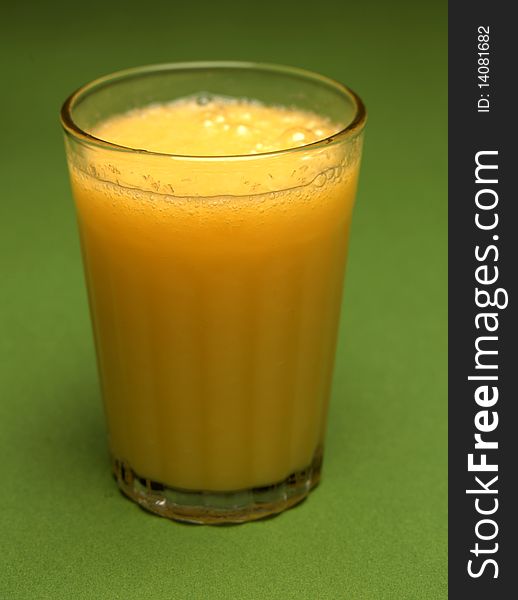 A glass of orange juice on green background. A glass of orange juice on green background