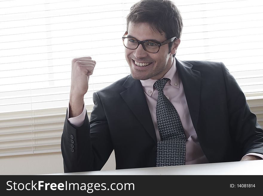 Businessman celebrating, fists raised, in the office. Businessman celebrating, fists raised, in the office