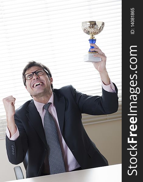 Businessman celebrating raising a cup. Concept: winning the challenge/emerging