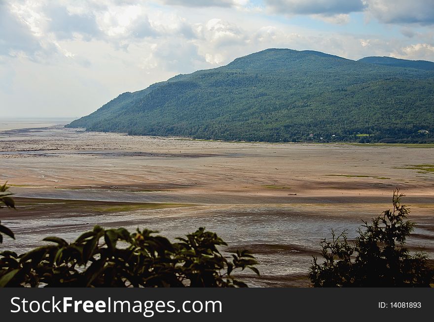 People in the far background walking on the beach of St Lawrence river at ebb tide, Charlevoix, Quebec