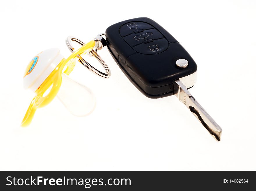A yellow pacifier attached to a black car key against a white background.