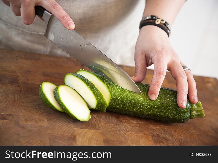 Female chef cutting slices of fresh zucchini. Female chef cutting slices of fresh zucchini