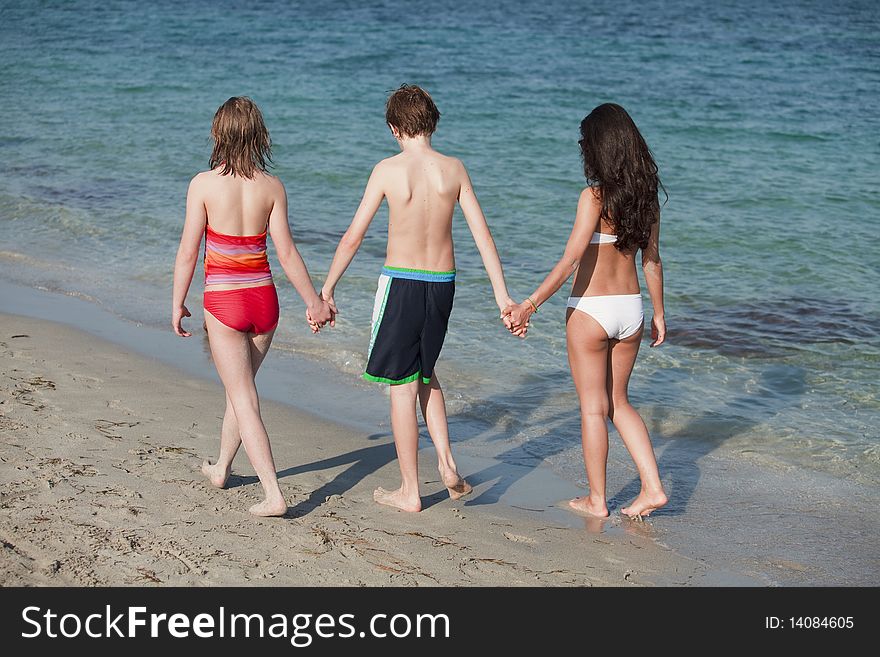 Three Teenagers holding hands enjoying a walk along the shoreline of beautiful Miami Beach. Three Teenagers holding hands enjoying a walk along the shoreline of beautiful Miami Beach.