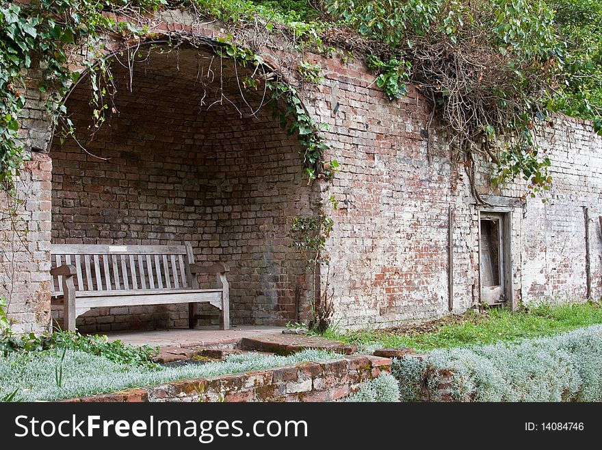 A garden bench in a secluded shelter set into a brick wall. A garden bench in a secluded shelter set into a brick wall