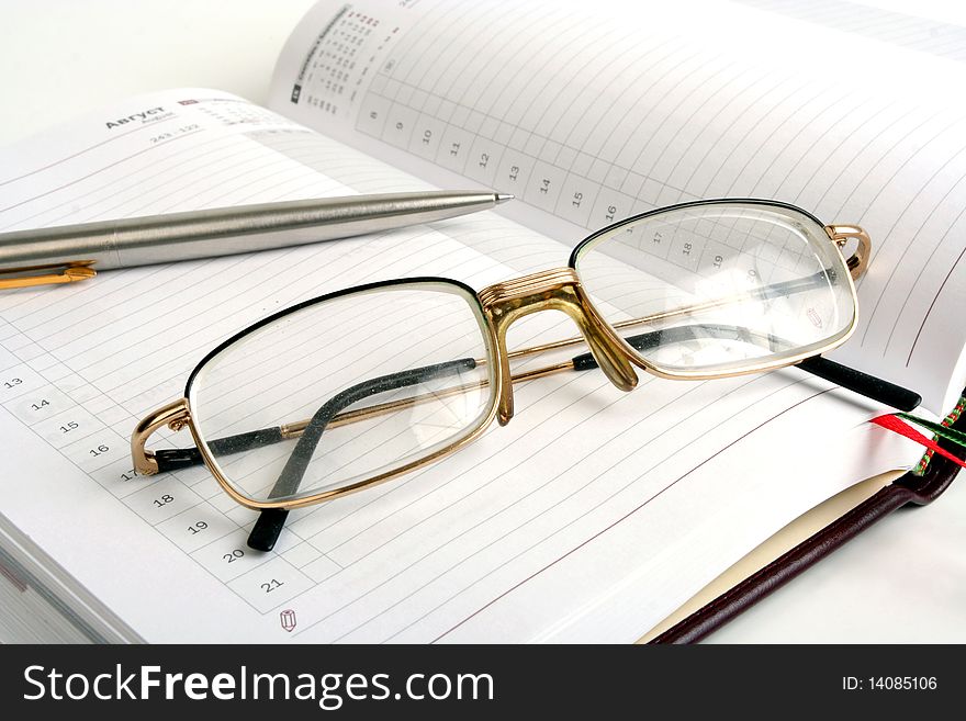 Notebook, pen and eyeglasses on white background