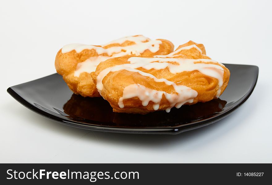 Two pastries filled with custard on black plate on white background. Two pastries filled with custard on black plate on white background