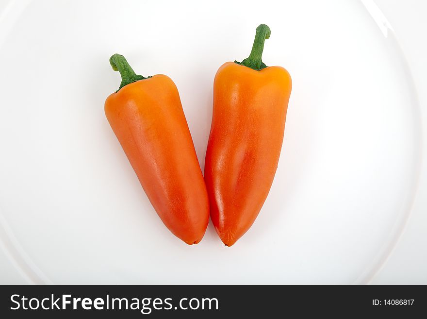 Two sweet orange peppers in white plate. Two sweet orange peppers in white plate.