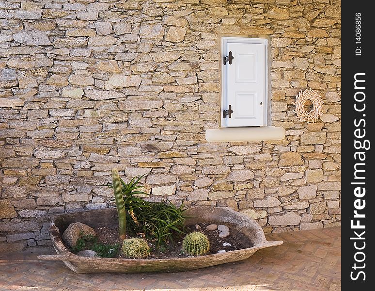 Bed with a cactus in a tub near the wall of rough stone near the window. Bed with a cactus in a tub near the wall of rough stone near the window