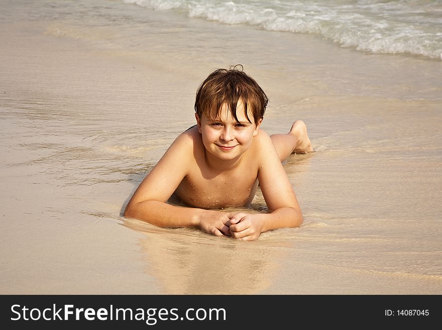 Boy is y lying at the beach and enjoying the warmness of the water and looking self confident and happy. Boy is y lying at the beach and enjoying the warmness of the water and looking self confident and happy