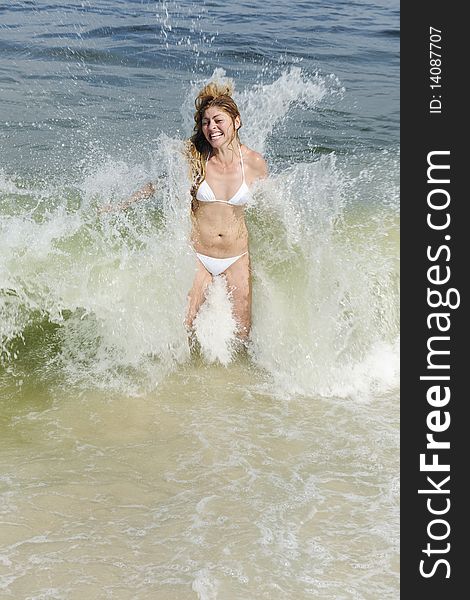 Summer vacation fun: young woman being splashed by a wave