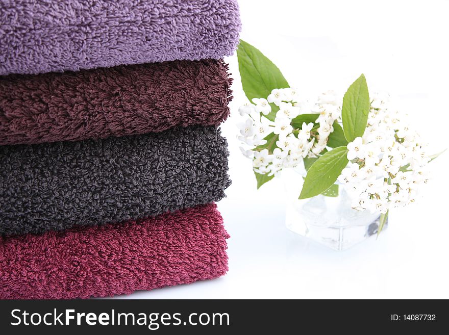 Stack of towels of cotton terry and small vase of white lilac