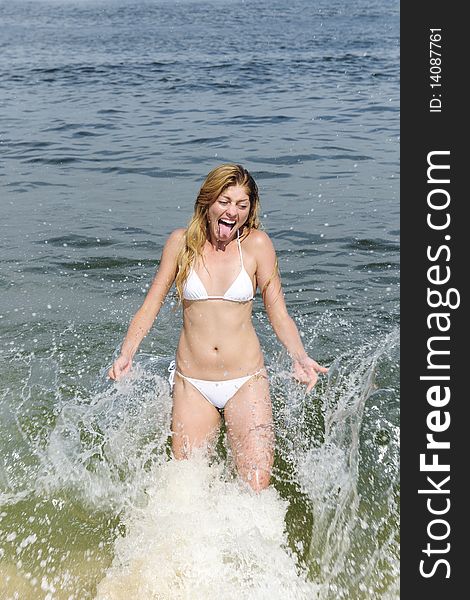 Summer vacation fun: young woman being splashed by a wave