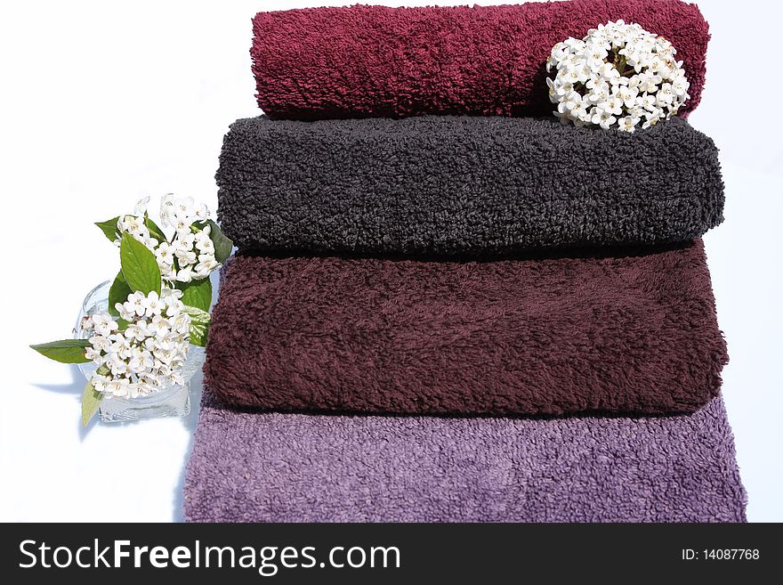 Stack of towels of cotton terry and small vase of white lilac