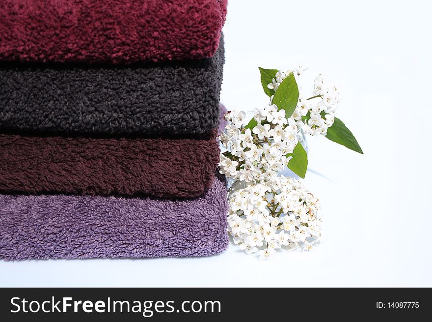 Stack of towels of cotton terry and small vase of white lilac