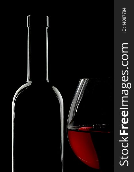 Bottle and glass of red wine over black background. Copy space on top.