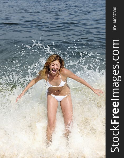 Summer vacation fun: young woman being splashed by a wave