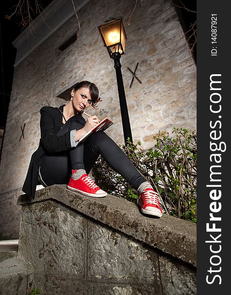 Beautiful young girl sitting on the wall