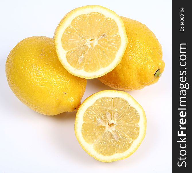 Three lemons, one cut in half, on white background