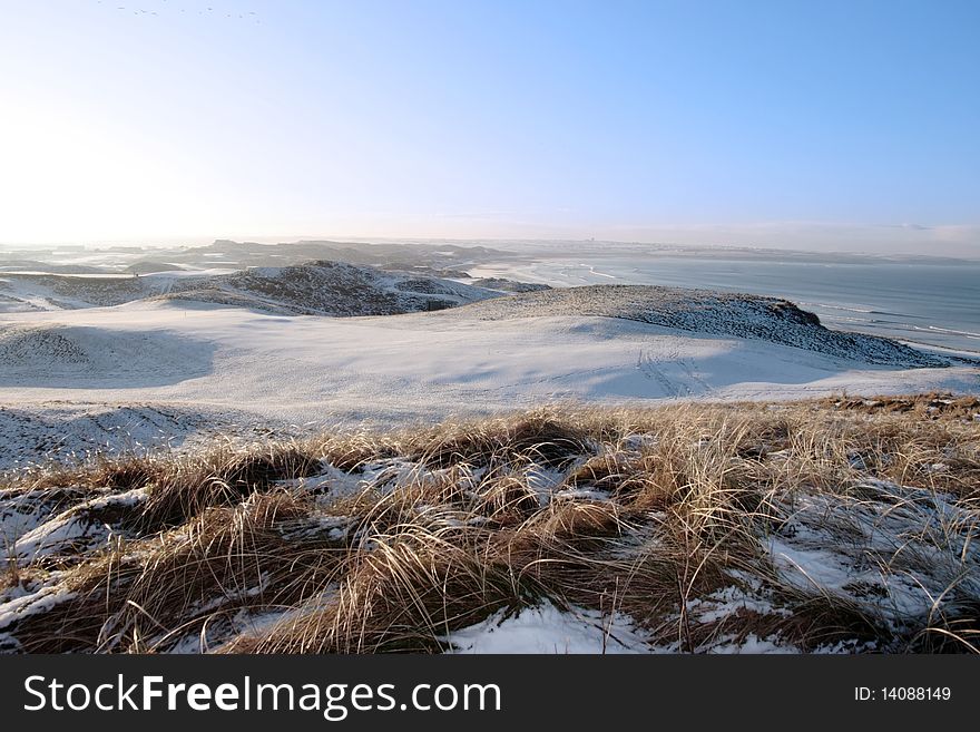 Icy snow covered links golf course and sea