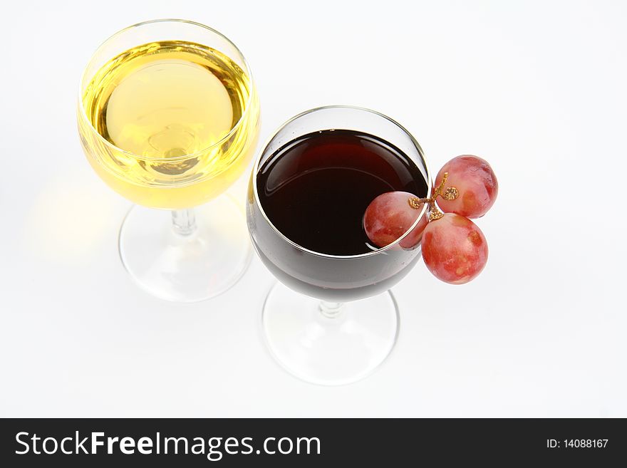 Red and white wine in wineglasses with three red grapes on white background
