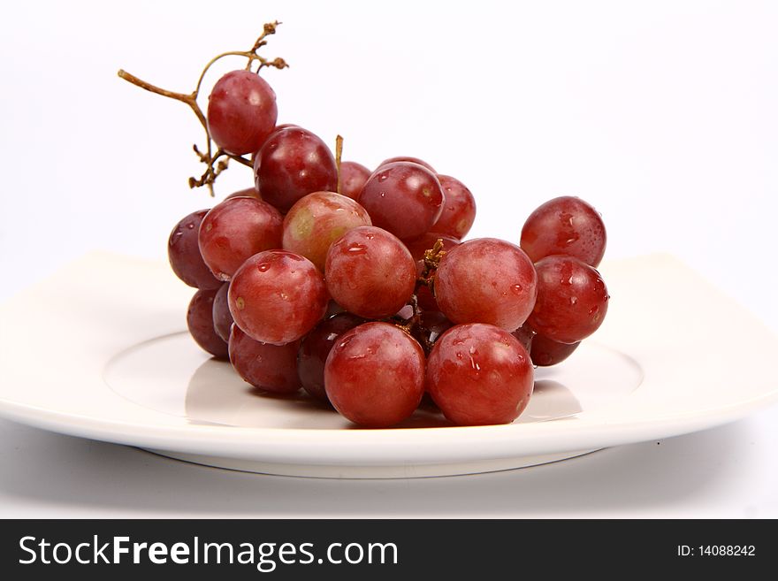 Red grapes on a plate on white background