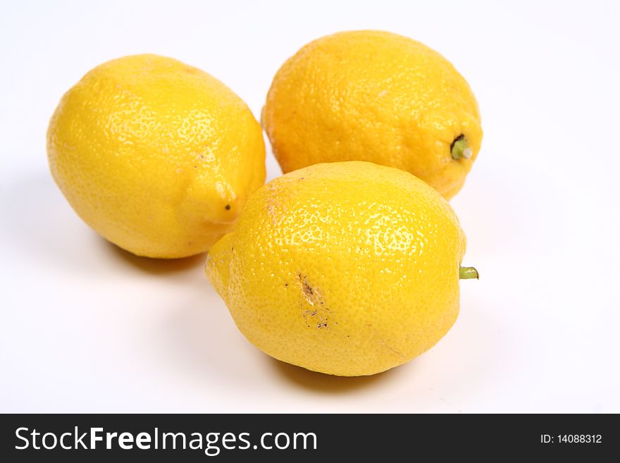 Three ripe yellow lemons on white background
