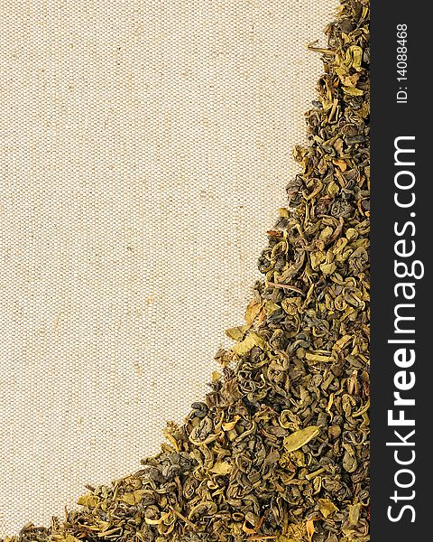 Dry green tea leaves on a sackcloth, horizontal background