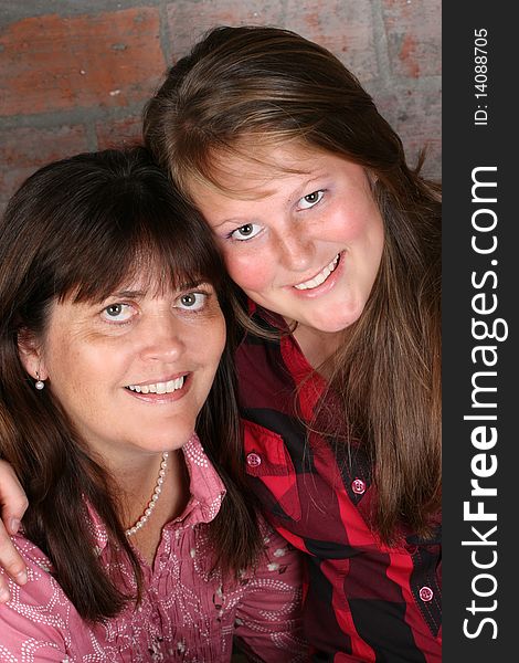 Beautiful mother and daughter against a brick-wall background. Beautiful mother and daughter against a brick-wall background