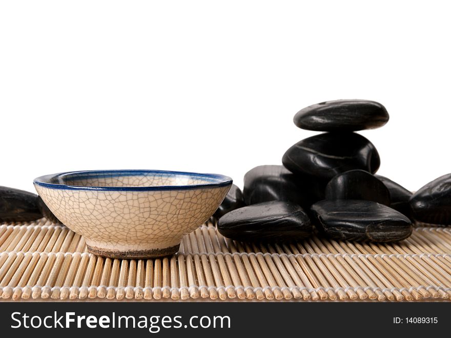 Some dark stones and cup for tea lie on mat