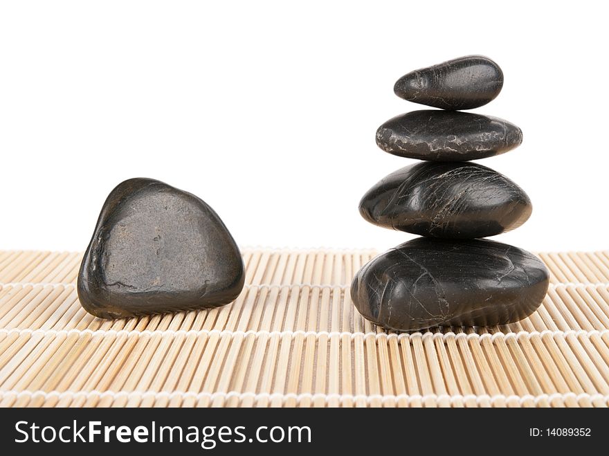 Some stones lie pyramid on mat isolated in white