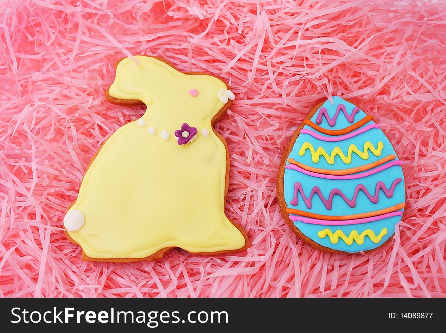 Close up of easter egg and bunny cookies on pink ribbons as background. Close up of easter egg and bunny cookies on pink ribbons as background.