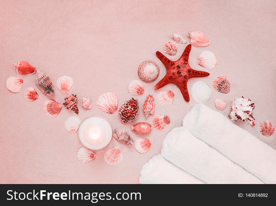 Red starfish and mollusk shells on pure white fine beach sand. Burning candle and three rolls of clean spa salon bath towels.Sea relax background with place for text, copy space. Top view, copy space. Red starfish and mollusk shells on pure white fine beach sand. Burning candle and three rolls of clean spa salon bath towels.Sea relax background with place for text, copy space. Top view, copy space